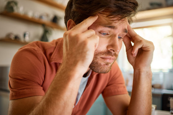 Man looking stressed and worried at home, surrounded by fancy designer socks implying possible cheating.