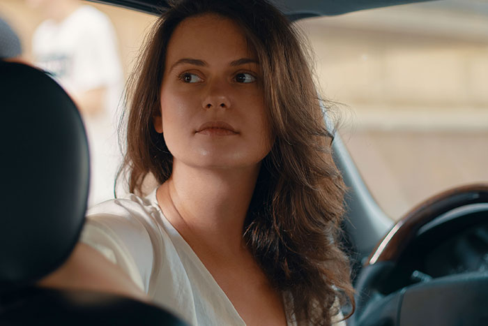 Woman refusing to drive a car until all friends buckle seat belts in a tense road trip situation.