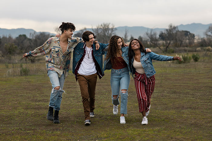 Group of friends walking together outdoors, highlighting woman refusing to drive until all friends buckle seat belts.