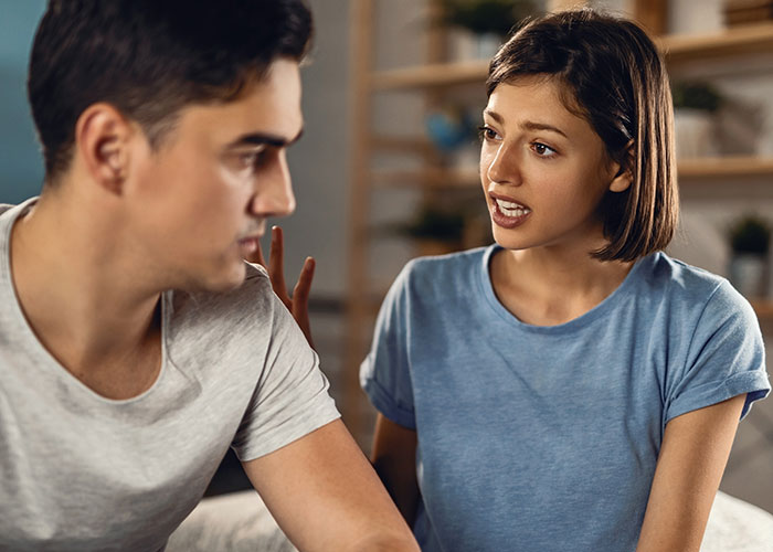 Woman feels treated like an unpaid nanny, talking seriously to partner who looks away during a home conversation.