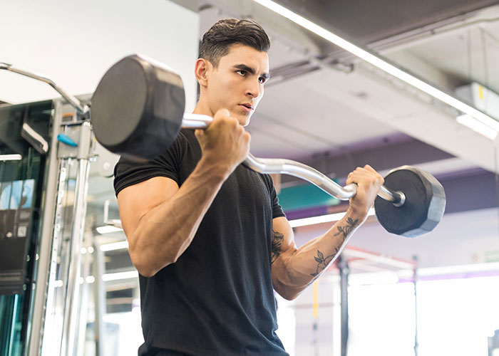 Man lifting weights at the gym while woman feels treated like unpaid nanny caring for child at home