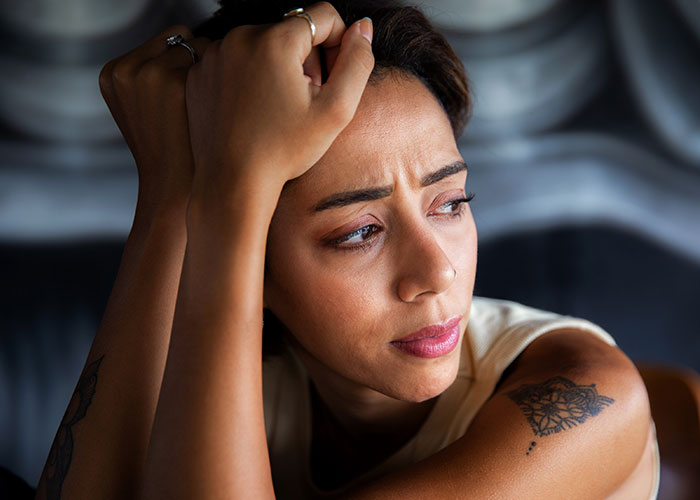 Woman looking distressed and tired, feeling treated like an unpaid nanny after partner leaves child to go to the gym.