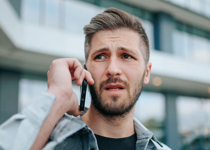 Man looking concerned while talking on phone outdoors, illustrating feelings of being treated like an unpaid nanny.