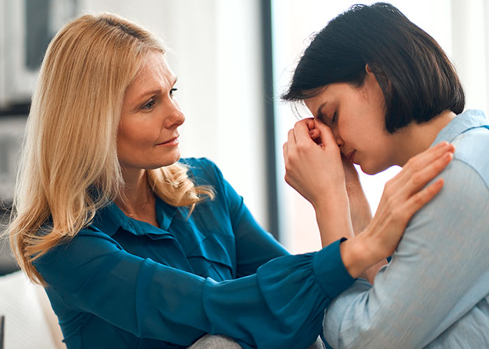 Woman feeling treated like unpaid nanny comforts stressed partner in emotional moment at home after child care issue.
