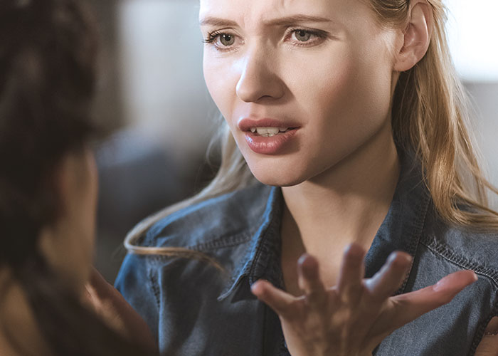 Close-up of a distressed woman expressing frustration in a tense conversation about obsession and stalking issues.