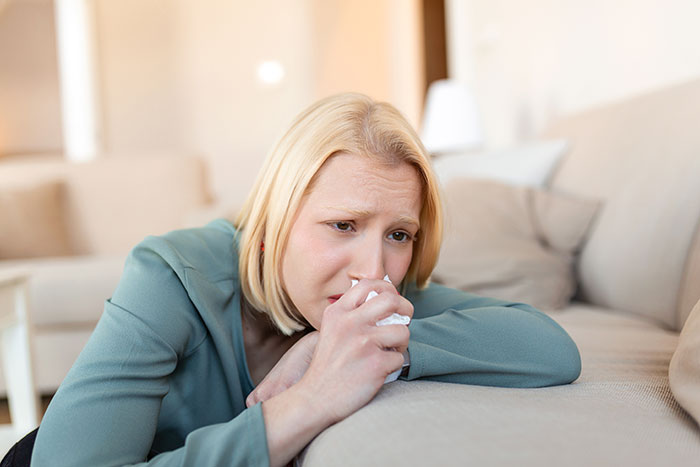 Woman upset on couch holding tissue, reflecting on a complicated 4-year-old relationship as mistress revelation unfolds.