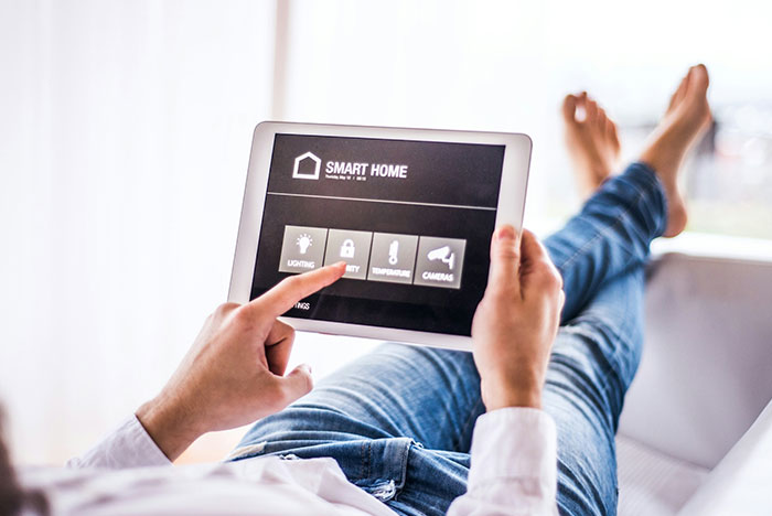 Man using smart home tablet controlling lighting and security, noticing strange things happening in apartment.