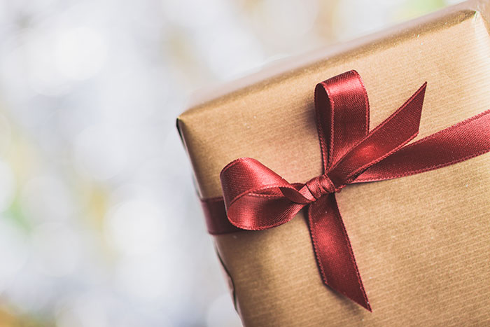 Close-up of a Christmas gift wrapped in brown paper with a red ribbon, symbolizing confusing Christmas gifts from boyfriend.