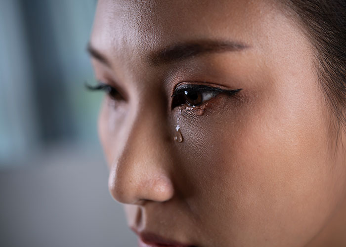 Close-up of a woman with a tear on her cheek, reflecting emotions from protecting her new career and seeing true colors.