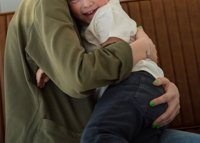 Woman with green nail polish hugging child, illustrating love is a verb and family care despite struggles.