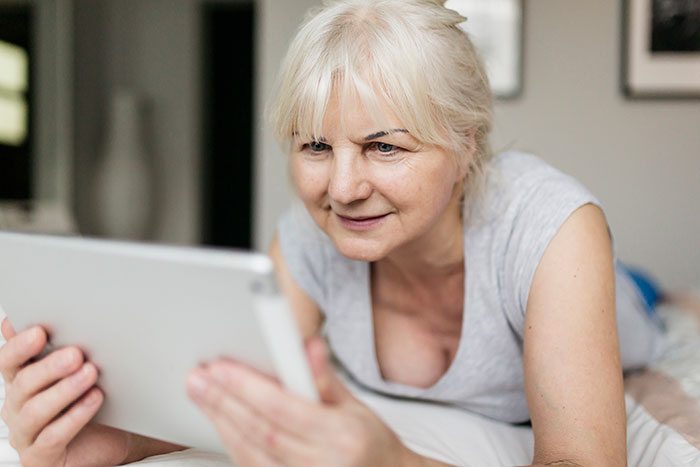 Older woman looking uncomfortable while viewing content on a tablet, illustrating woman uncomfortable mil AI images concept.
