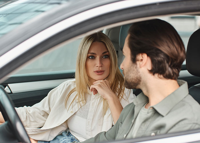 Woman and man in a car having a serious conversation, illustrating tension in a friendship over engagement party plans.
