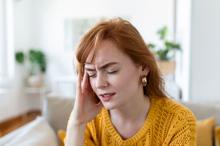Daycare worker feeling stressed and confused indoors, reacting to a possible passive-aggressive coworker gift situation.