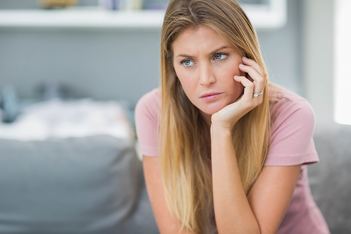 Daycare worker looking thoughtful and concerned, sitting indoors, reflecting on a passive-aggressive coworker gift incident