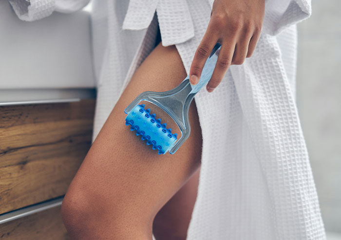 Woman using a blue massage roller on her thigh, illustrating what women obsess over for no reason at all