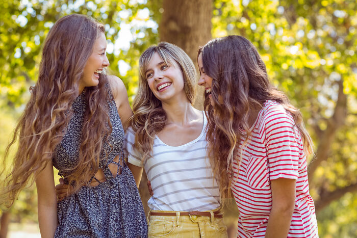 Three women smiling and laughing together outdoors challenged misconceptions about women men have to put to rest.