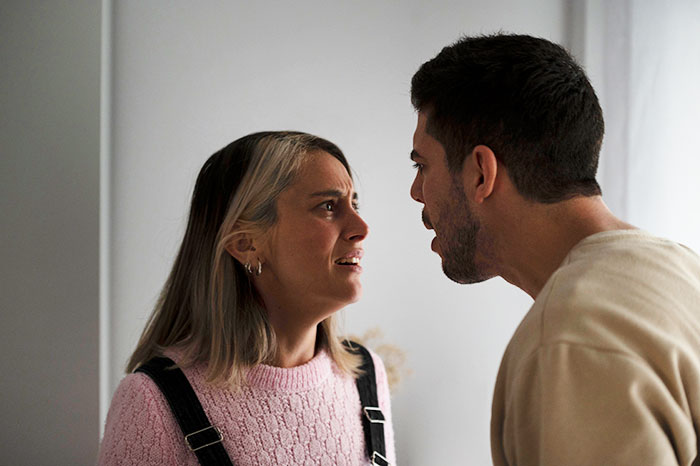 Man and woman arguing in a tense moment, highlighting confusion over a business trip versus a romantic getaway.