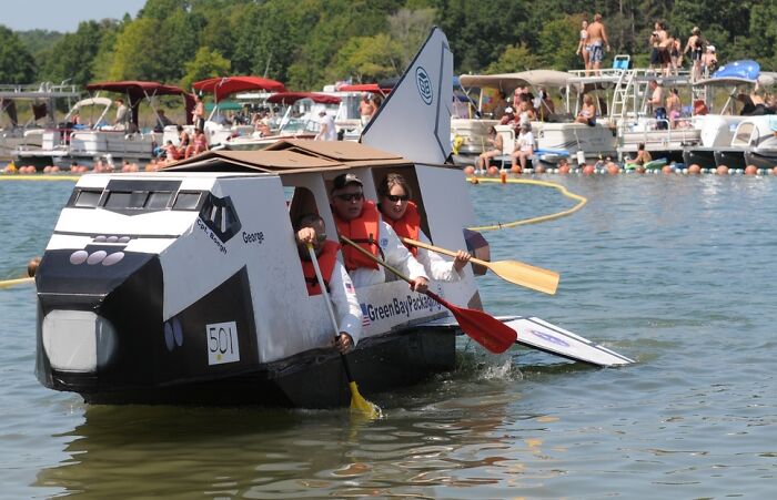 Two people paddling a boat shaped like a spaceship, part of strange and unusual traditions from around the world.