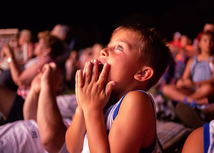 Young boy in a crowd looking amazed and praying, capturing a moment of being in the wrong place at the wrong time.
