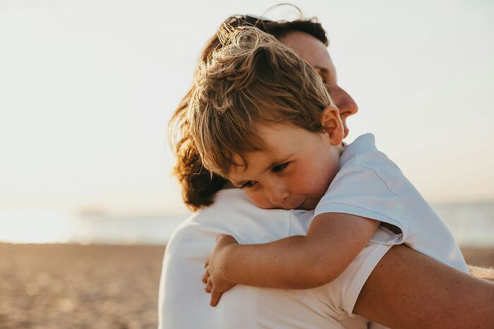 Child hugging adult on beach at sunset, illustrating themes of parenting and nannies and the internet influence.