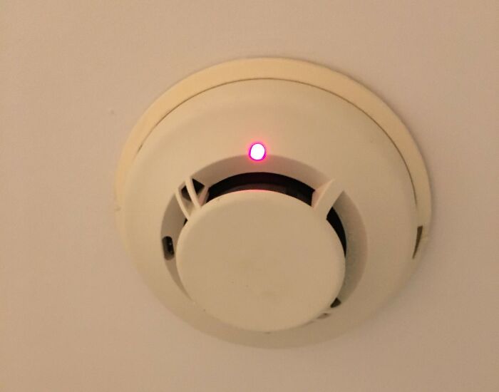 Smoke detector with a red indicator light installed on the ceiling, relevant to shipping containers safety solutions.