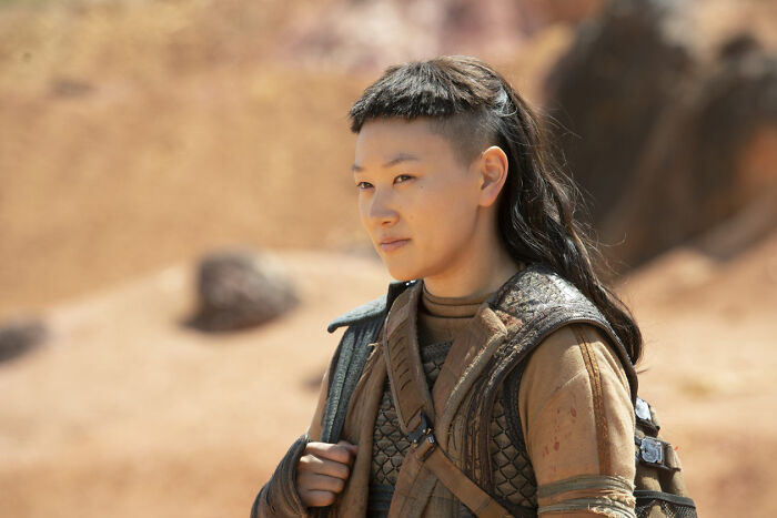 Actress behind Sophie Baek in Bridgerton wearing costume in an outdoor desert-like setting, looking contemplative. Actress behind Sophie Baek in Bridgerton wearing costume in an outdoor desert-like setting, looking contemplative.