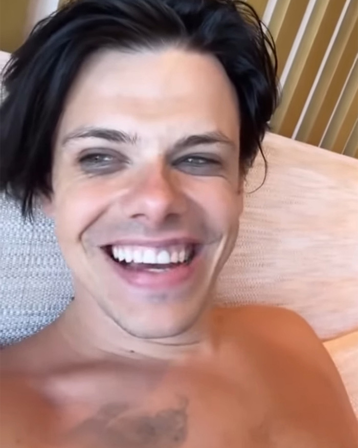 Yungblud smiling shirtless indoors, revealing consequences of stripping down on yacht after viral stunt.