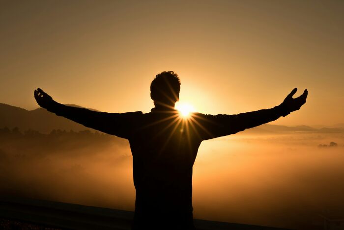 Silhouette of a person with arms outstretched at sunrise, symbolizing cheat codes to make everyday life easier.