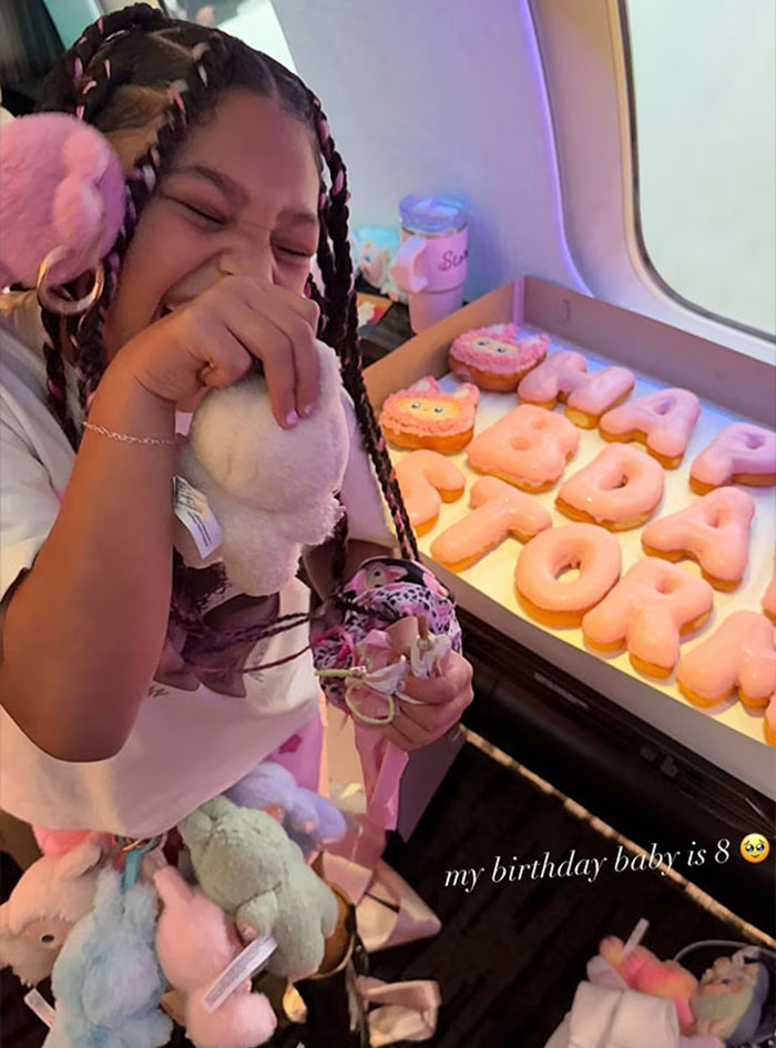 Child celebrating with plush toys and cookies spelling birthday theme, linked to Travis Scott and Kylie Jenner controversy.
