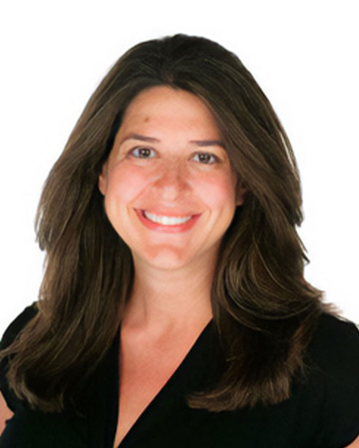 Smiling woman with long brown hair in black top, representing teacher's hot-mic moment sparking outrage among students.
