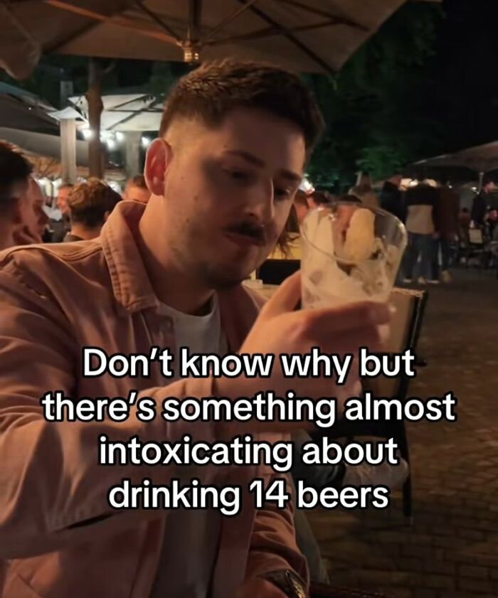 Young man holding a beer glass at an outdoor bar, reflecting with a hint of cynicism in a hilarious meme.