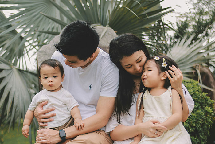 Family of four outdoors, parents embracing and comforting children, highlighting Frida Mom marketing controversy.