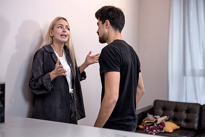 A couple arguing intensely inside a living room over a family conflict and moving in together.