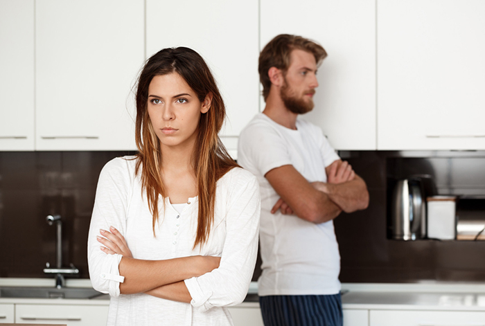 Wife stands up for herself looking determined while man with submissive nature appears upset in modern kitchen setting