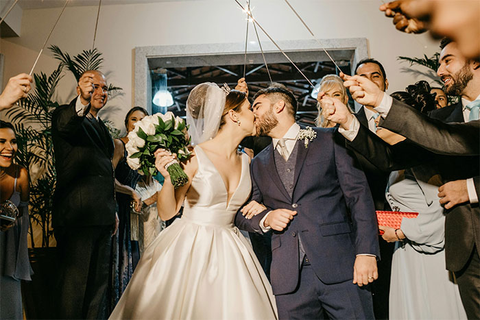 Bride and groom kissing while wedding guests celebrate around them in a festive scene showing sister refuses plan wedding tension.