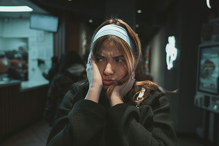 Young woman looking upset and frustrated indoors, reflecting emotions after sister insults her in a tense family moment.