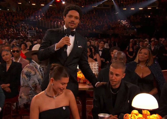 Trevor Noah in tuxedo speaking with Justin Bieber and a woman seated, capturing body language expert analysis moment. Trevor Noah in tuxedo speaking with Justin Bieber and a woman seated, capturing body language expert analysis moment.