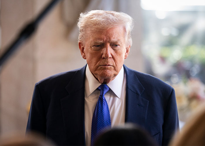 Donald Trump in a dark suit and blue tie, with a serious expression, related to Epstein investigation and FBI documents.