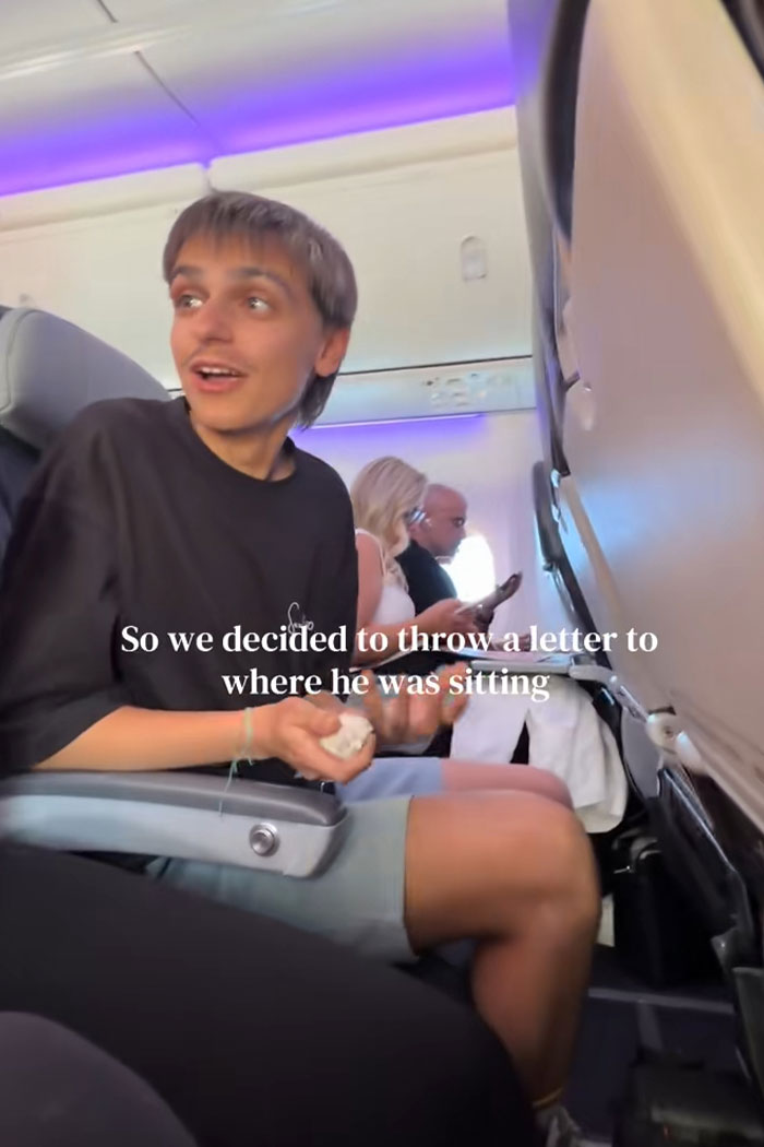 Young man sitting on an airplane reacting as Australian woman writes love note to cute guy she spotted on flight. Young man sitting on an airplane reacting as Australian woman writes love note to cute guy she spotted on flight.