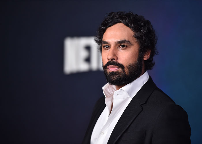 Kunal Nayyar from The Big Bang Theory at a formal event, with a serious expression and dark background.