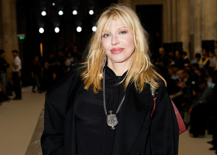 Courtney Love attending an event, dressed in black, with blonde hair, related to Kurt Cobain homicide claim reaction.