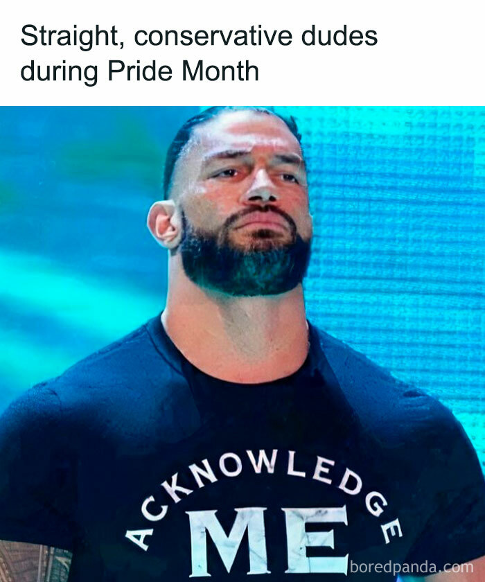 Man with beard and intense expression wearing a black shirt with the words acknowledge me in a hilarious meme style.