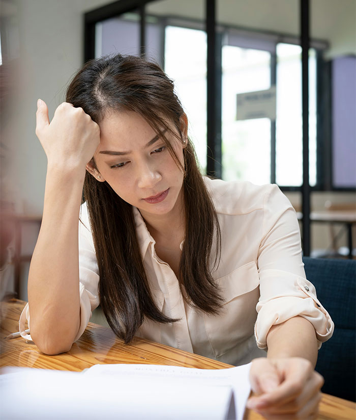 Woman looking frustrated at paperwork, representing refusal to contribute to a coworker's retirement gift after workplace misery.