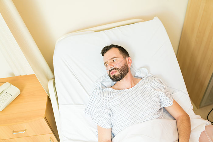 Man with nasal cannula lying in hospital bed, reflecting on family kidney request and difficult brother sacrifice.