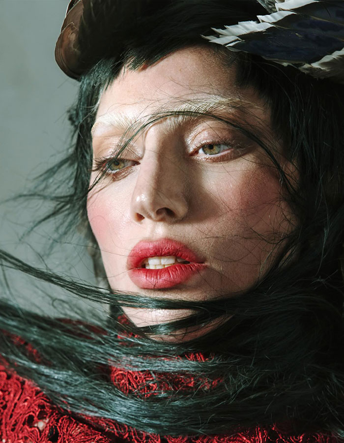 Close-up portrait of a woman with dark hair, red lipstick, and intricate headpiece, evoking Lady Gaga Epstein ties discussion.