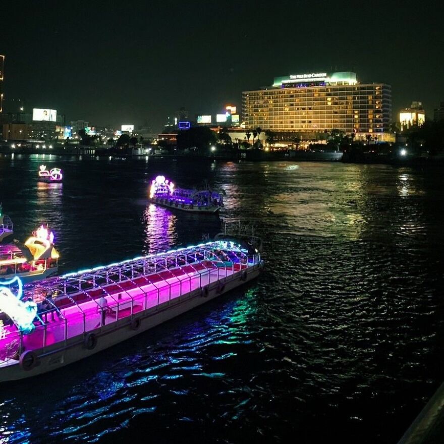 Night cityscape with brightly lit boats on the river, showcasing vibrant nightlife in cities where sleep is optional.