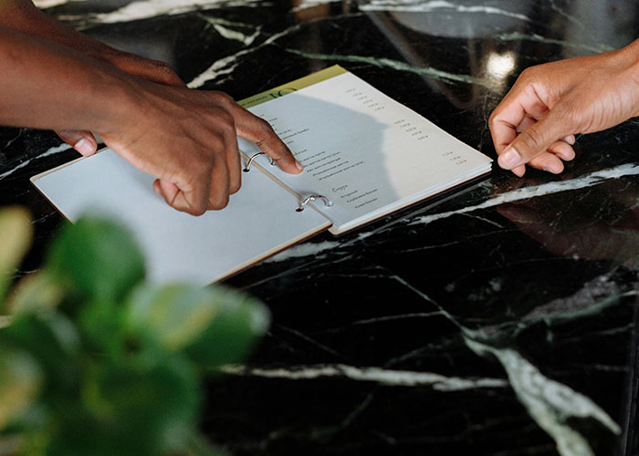 Two hands pointing at a menu on a marble table, highlighting practical things countries have that make sense.