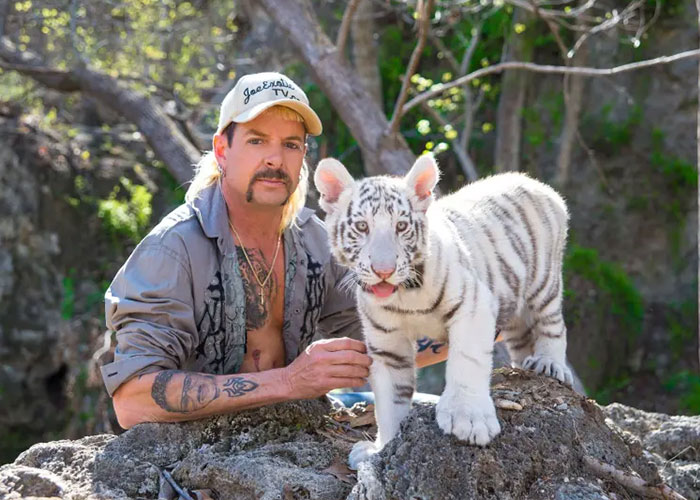 Joe Exotic outdoors with a white tiger cub, illustrating viral content on Epstein files and internet buzz.