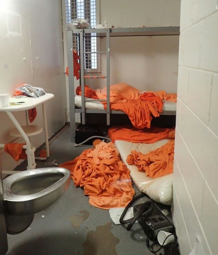 Prison cell with messy orange blankets and metal bed, related to doctor at Jeffrey Epstein's post mortem claims. Prison cell with messy orange blankets and metal bed, related to doctor at Jeffrey Epstein's post mortem claims.
