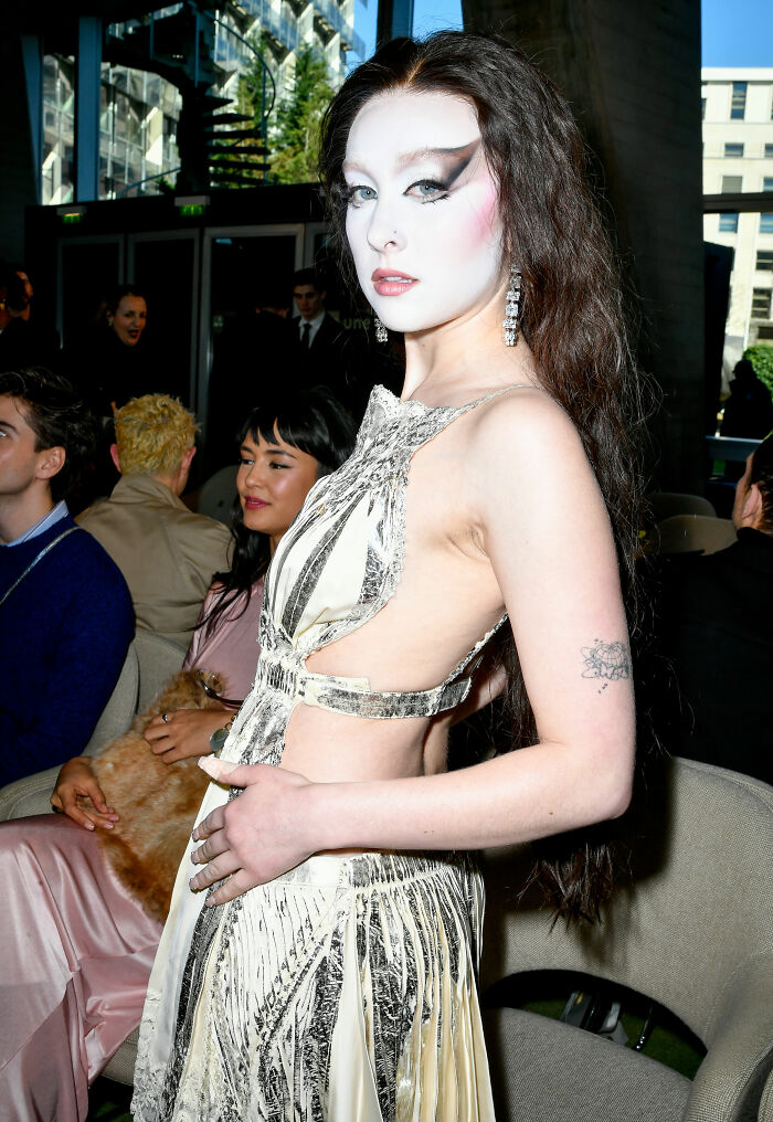 Chappell Roan at an event wearing a bold silver and cream dress with dramatic makeup, embodying brain malfunction style.